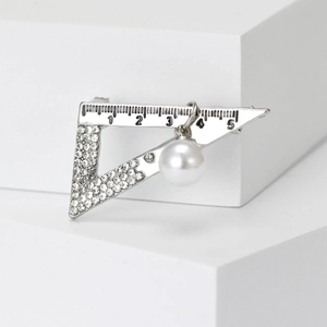 Detail of silver alloy triangle ruler brooch with white rhinestones and a pearl drop