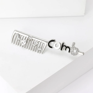 Detail view of silver comb brooch with rhinestones and creative lettering design