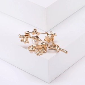 Vue détaillée du dos d'une broche branche dorée avec des perles blanches et un fermoir épingle