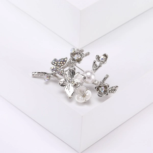 Vue macro de la broche papillon argentée avec perle blanche et strass étincelants