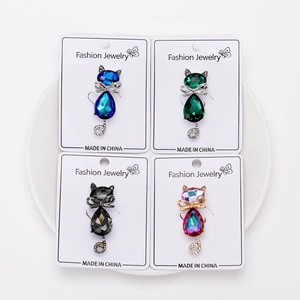 Macro shot of 4 crystal cat brooches in blue, green, black and pink with bow details