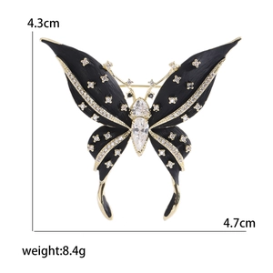 Elegante spilla a farfalla nera con zirconi micro-pavé e bordo dorato per abiti