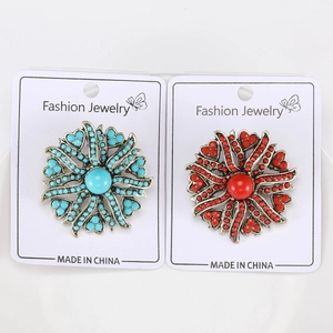 Detail view of vintage alloy sunflower brooches in red and blue on jewelry card