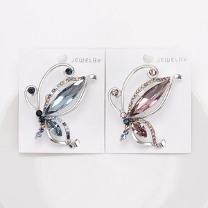 Elegant crystal butterfly brooches in grey-blue and light pink colors on a white tray
