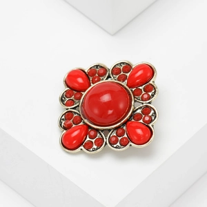 Macro shot of vintage bronze brooch with large central red bead and textured grain metalwork
