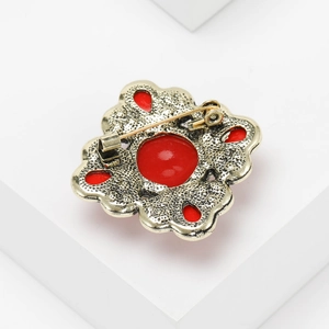 Detail view of vintage gold brooch back showing secure metal pin and red gemstones