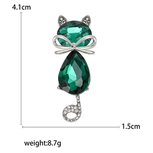 Elegant cat brooch with green crystals and crystal bow on a white background
