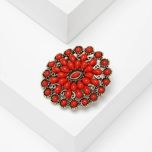 Vue détaillée de la broche fleur vintage avec pétales en résine rouge et base dorée antique