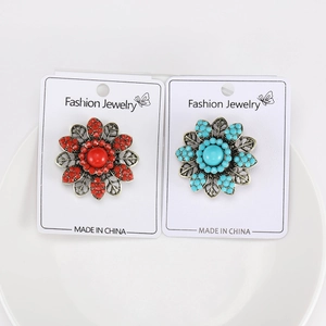 Macro shot of vintage flower brooches with red and turquoise stones on display cards