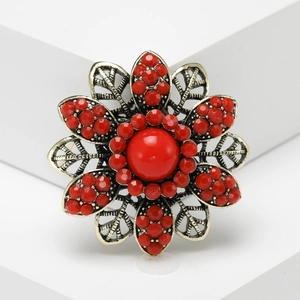 Vintage bohemian flower ring in antique gold with red rhinestones on white pedestal