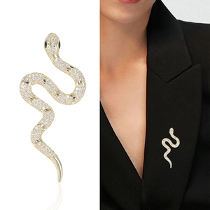 Broche serpent dorée élégante avec zircons blancs sur le revers d'un blazer noir