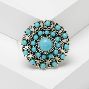 Baroque vintage brooch with turquoise beads and gold alloy filigree on a white stand
