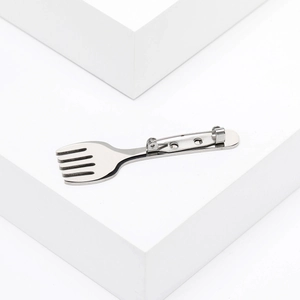 Detailed view of the silver creative fork brooch on a white geometric block base