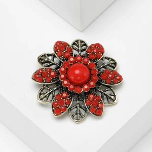 Macro shot of vintage bronze flower brooch with vibrant red crystals and beads