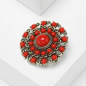 Detail of baroque brooch with antique gold hollow patterns and large red center beads