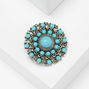 Detail of baroque vintage round brooch with turquoise beads on ornate silver base