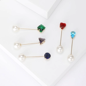 Vista detallada de broches de perlas minimalistas con gemas de colores en cubos blancos