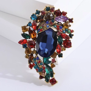 Close-up of vintage alloy brooch featuring large blue gemstone and colorful rhinestones