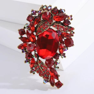 Macro shot of large red crystal brooch with vintage gold base and floral branch detail