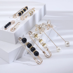 Ensemble d'épingles dorées avec perles et cristaux sur supports blancs minimalistes