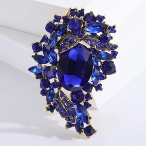 Vintage gold brooch with dark blue sapphire crystals on a white geometric display