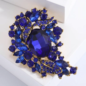 Macro shot of vintage gold alloy brooch featuring a deep blue oval faceted crystal
