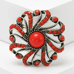 Vintage bronze flower brooch with central red gemstone and beaded petals on white block