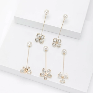 Broches élégantes en perles dorées avec charms papillon et fleurs sur fond blanc pur