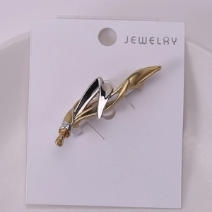 Detail of minimalist gold and silver two-tone abstract alloy brooch on white jewelry card