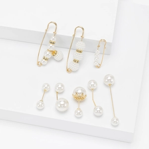 Elegant gold-tone pearl safety pin set with crystal accents on a white geometric stage