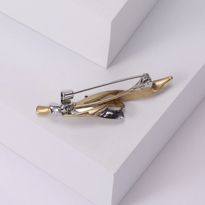 Minimalist minimalist gold and silver feather brooch with secure safety pin clasp on a base