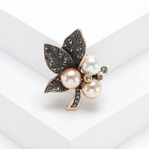 Vintage gold leaf brooch with grey crystals and elegant pearls on a geometric stand