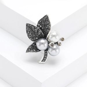 Vintage silver leaf brooch with marquise stones and pearls on a white geometric stand