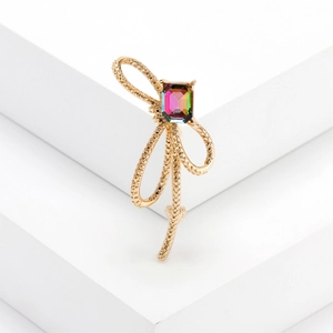 Broche nœud doré élégante avec strass dégradé sur support géométrique blanc