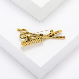 Macro detail of retro gold scissors and comb brooch on white geometric background