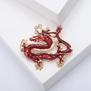 Detailed macro view of an enamel dragon brooch with intricate red and gold scaling details
