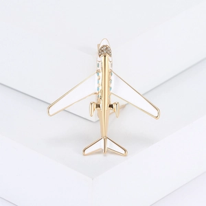 Spilla ad aereo dorata con ali in smalto bianco e strass su base geometrica moderna