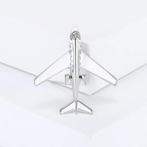 Spilla aereo creativa con smalto bianco e strass scintillanti su un supporto minimalista