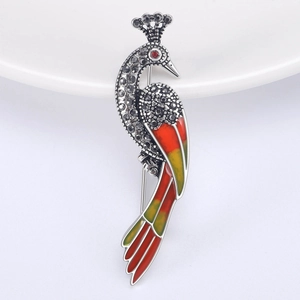 Vue détaillée de la broche paon avec strass noirs et émail rouge et jaune vif