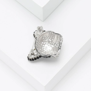 Back view of silver alloy dog brooch with rhinestones on a white geometric platform