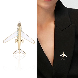 Elegante spilla aereo dorata con smalto bianco e strass sul risvolto di una giacca formale