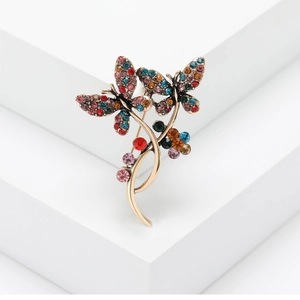 Vintage gold butterfly brooch with colorful rhinestones on a white geometric background