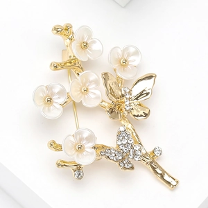 Détail de la broche branche papillon avec fleurs en nacre et strass étincelants de luxe