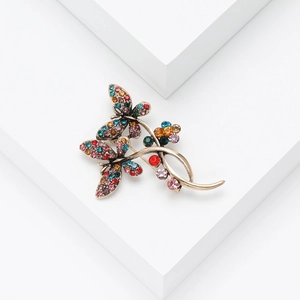 Macro detail of vintage gold butterfly brooch with multicolored rhinestones on white stands