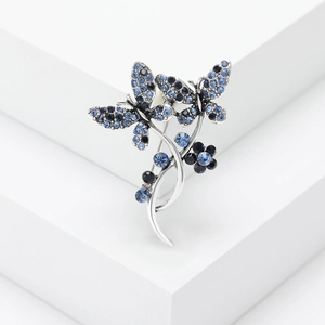Vintage butterfly and floral brooch with blue crystals on minimalist white background