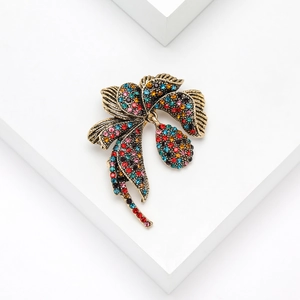 Close-up of vintage flower brooch with colorful rhinestones on a white pedestal