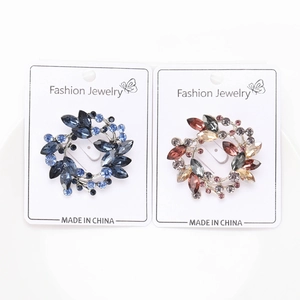 Detailed close-up of crystal olive branch wreath brooches in blue and amber tones