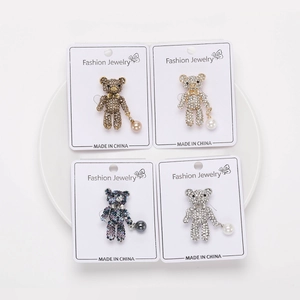 Gros plan de quatre broches ours en strass avec breloques perles en diverses couleurs
