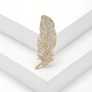 Elegante spilla a piuma dorata con strass scintillanti su supporto geometrico bianco