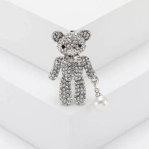 Detailed close-up of a silver teddy bear brooch with rhinestones and a white pearl drop